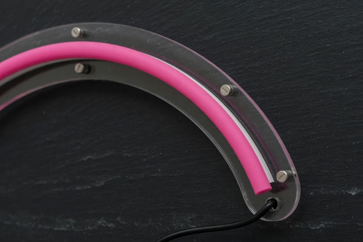 Détail d'un tube silicone rose magenta courbé, monté sur acrylique transparent découpé au contour