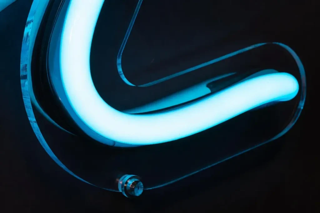 Dettaglio macro di un neon LED Helioneon in silicone flessibile da 6mm su supporto acrilico trasparente tagliato al laser, mostra la qualità costruttiva moderna
