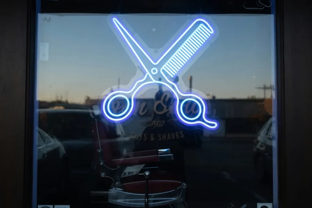 Néon LED ciseaux et peigne bleu en vitrine de barbershop