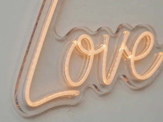 Close-up of the silicone tube of a custom neon “Love” on a light wall